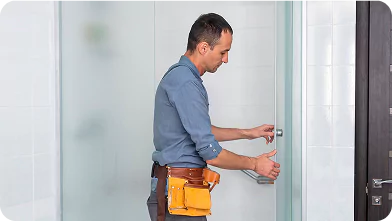 Maintenance technician adjusting a shower door inside a remote camp bathroom.