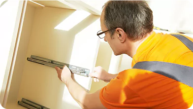 Maintenance technician fixing drawer rails inside a remote camp accommodation unit.