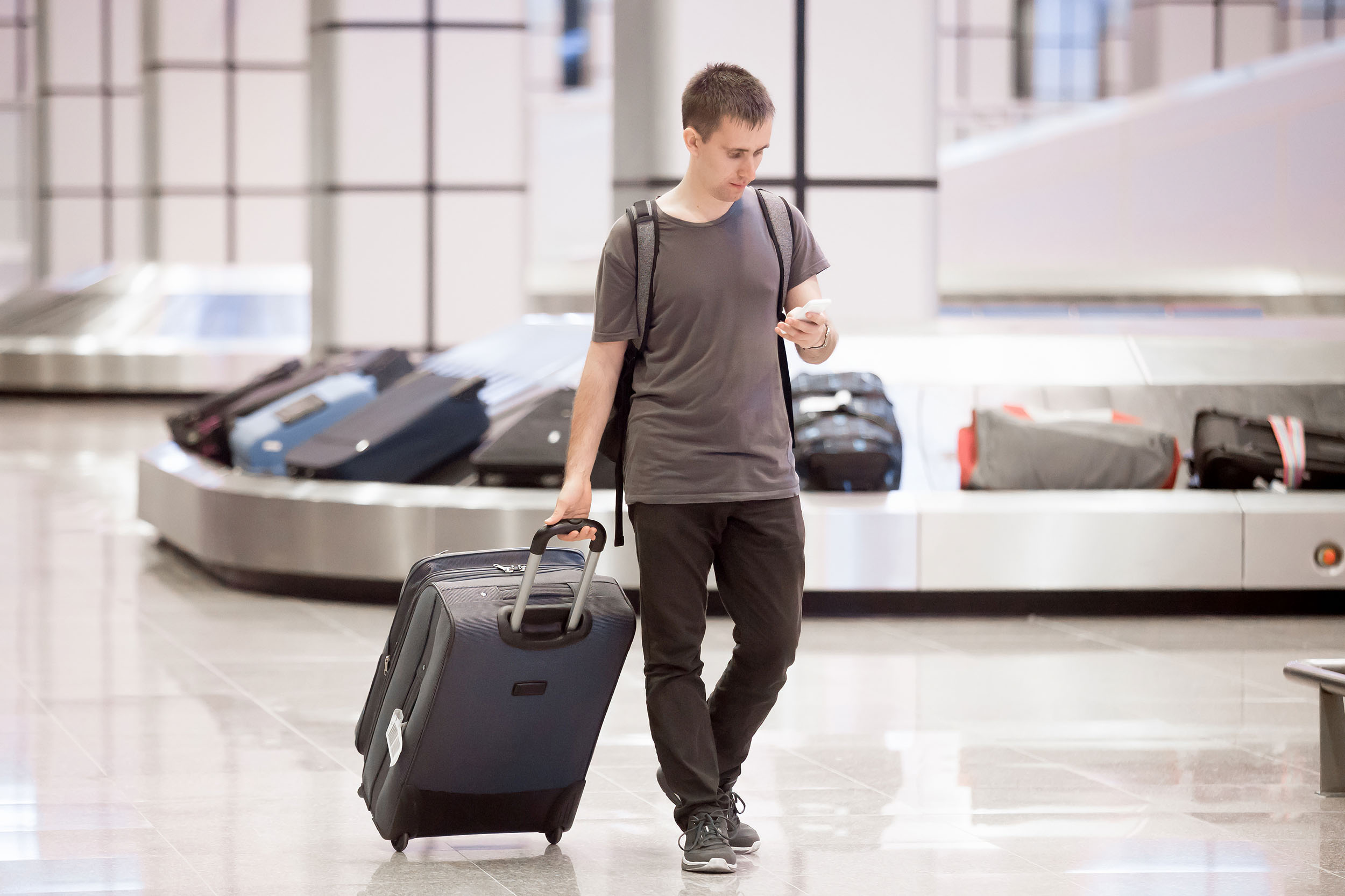 man-rolls-suitcase-baggage-carousel-area
