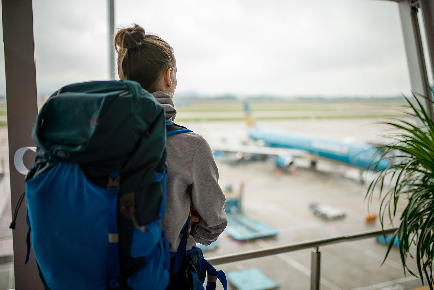 woman-backpack-looks-onto-plane-airport