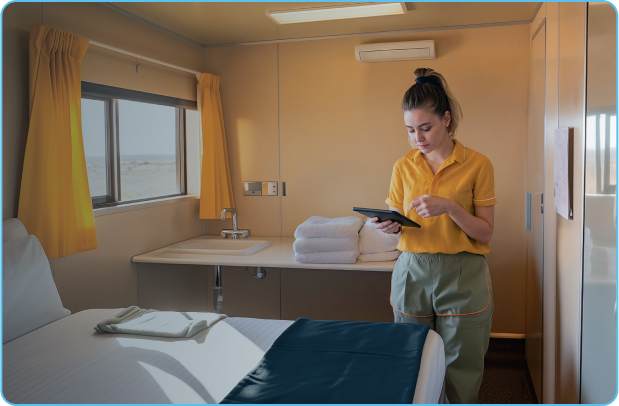 Camp attendant reads ipad inside bedroom at a remote mining camp.