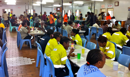 Workers wearing PPE eat dinner at mine camp