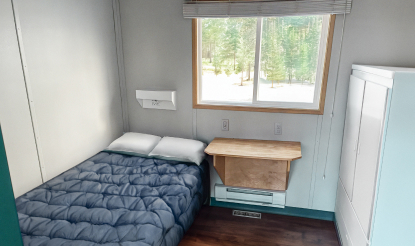 Mining camp bedroom with bed, desk and armoire