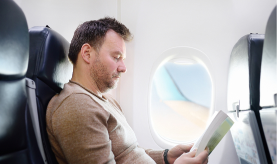 Fly-in fly-out worker reading on a plane during his journey to a remote worksite.