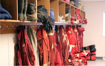 Boot room in an oilfield camp with worker uniforms and gear organized.