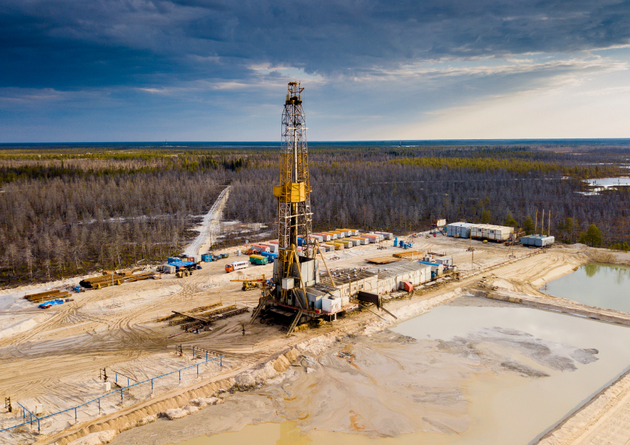 Onshore drilling rig located in a remote area surrounded by trees.