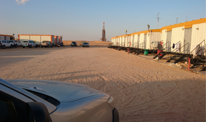 Truck driving into an oilfield housing facility in a desert setting in the Middle East.