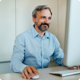 Male office worker dressed in business attire types at computer.