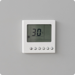 Thermostat attached to wall displays warm temperature.