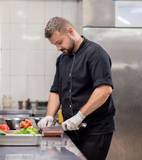 Cook prepares vegetables in an industrial kitchen.