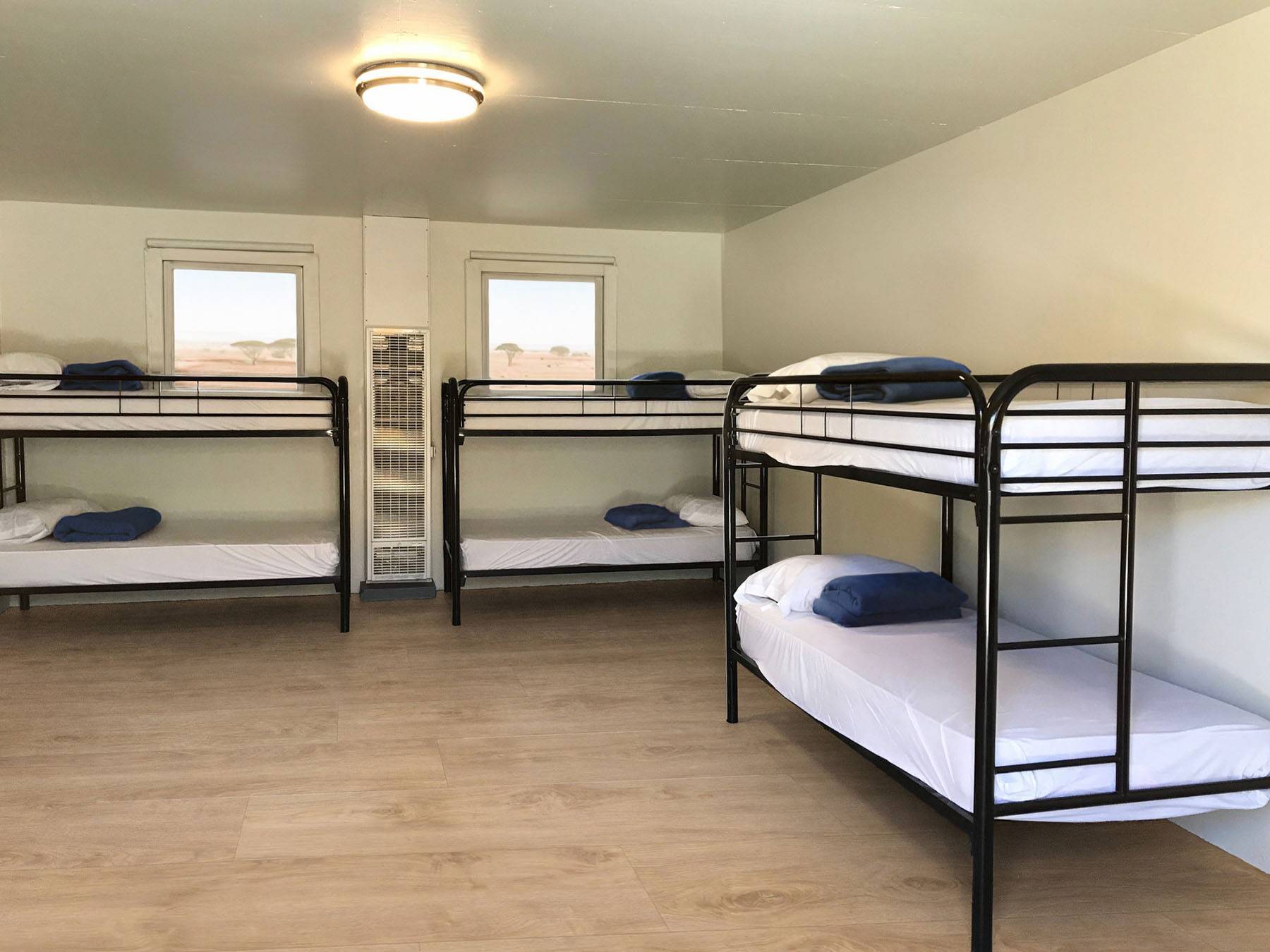 Bunk beds in a shared worker dormitory with windows looking onto a savannah.