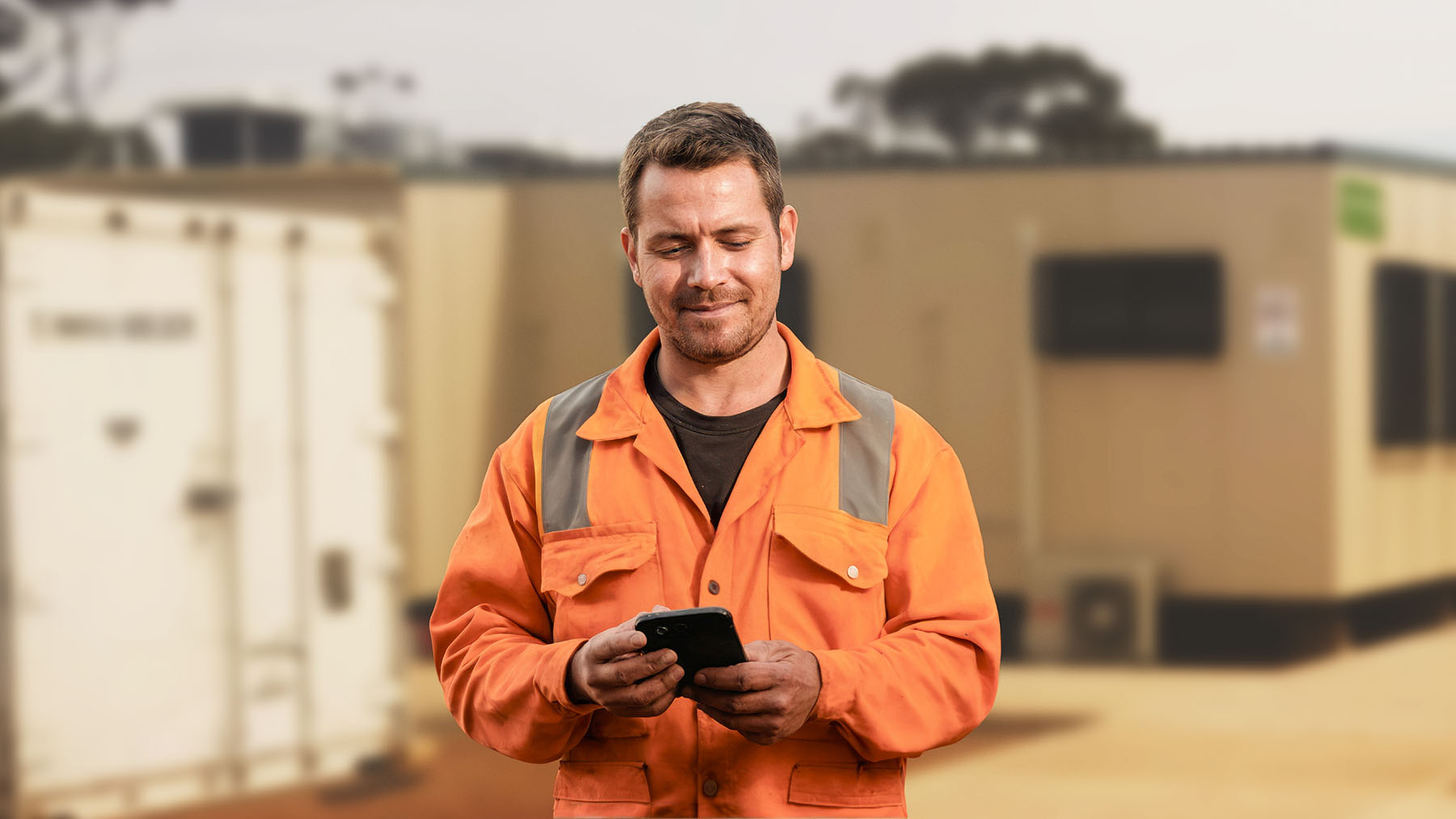 FIFO worker smiles while looking at cellphone outside.