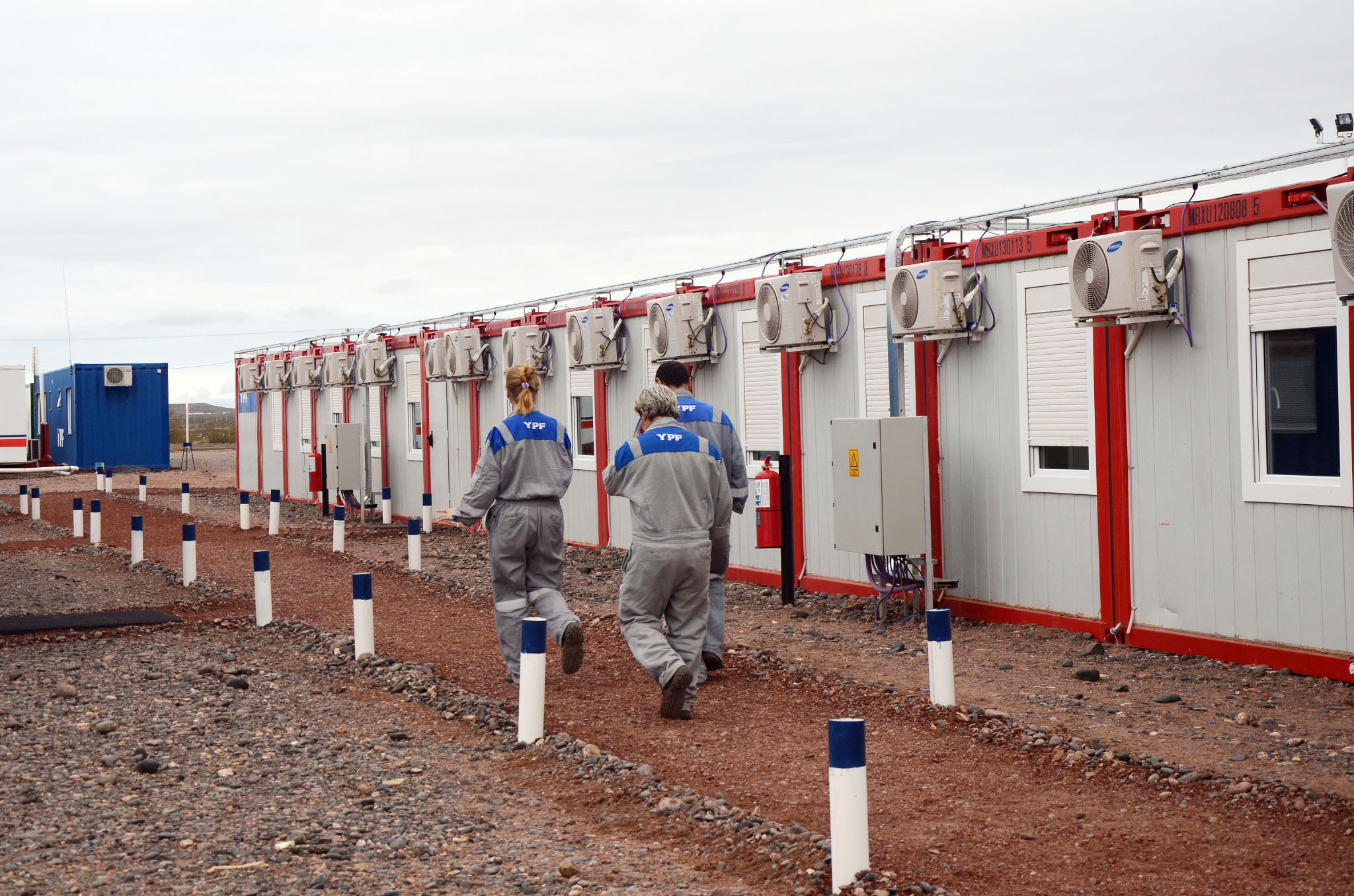 FIFO workers in uniform walk down a dirt path next to a portable modular structure.